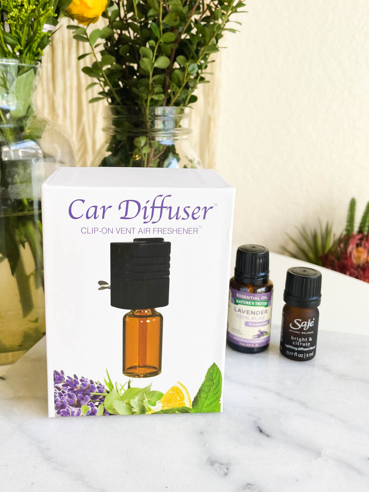 A box showing a car diffuser next to a few bottles of essential oils.