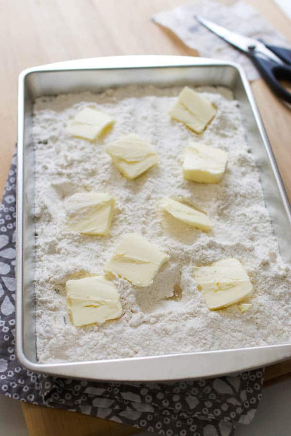 Pan of dump cake with the cake mix and butter chunks scattered over the top.