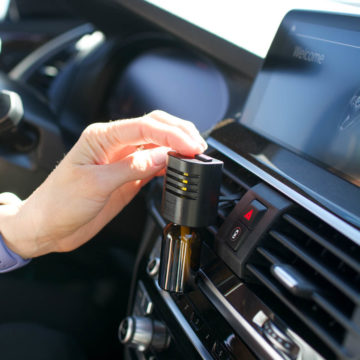 Car vent diffuser for essential oils with a woman sliding the open switch.