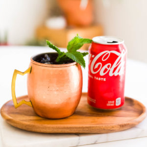 Close up of a Coke Moscow Mule in a copper mug next to a can of Coke.