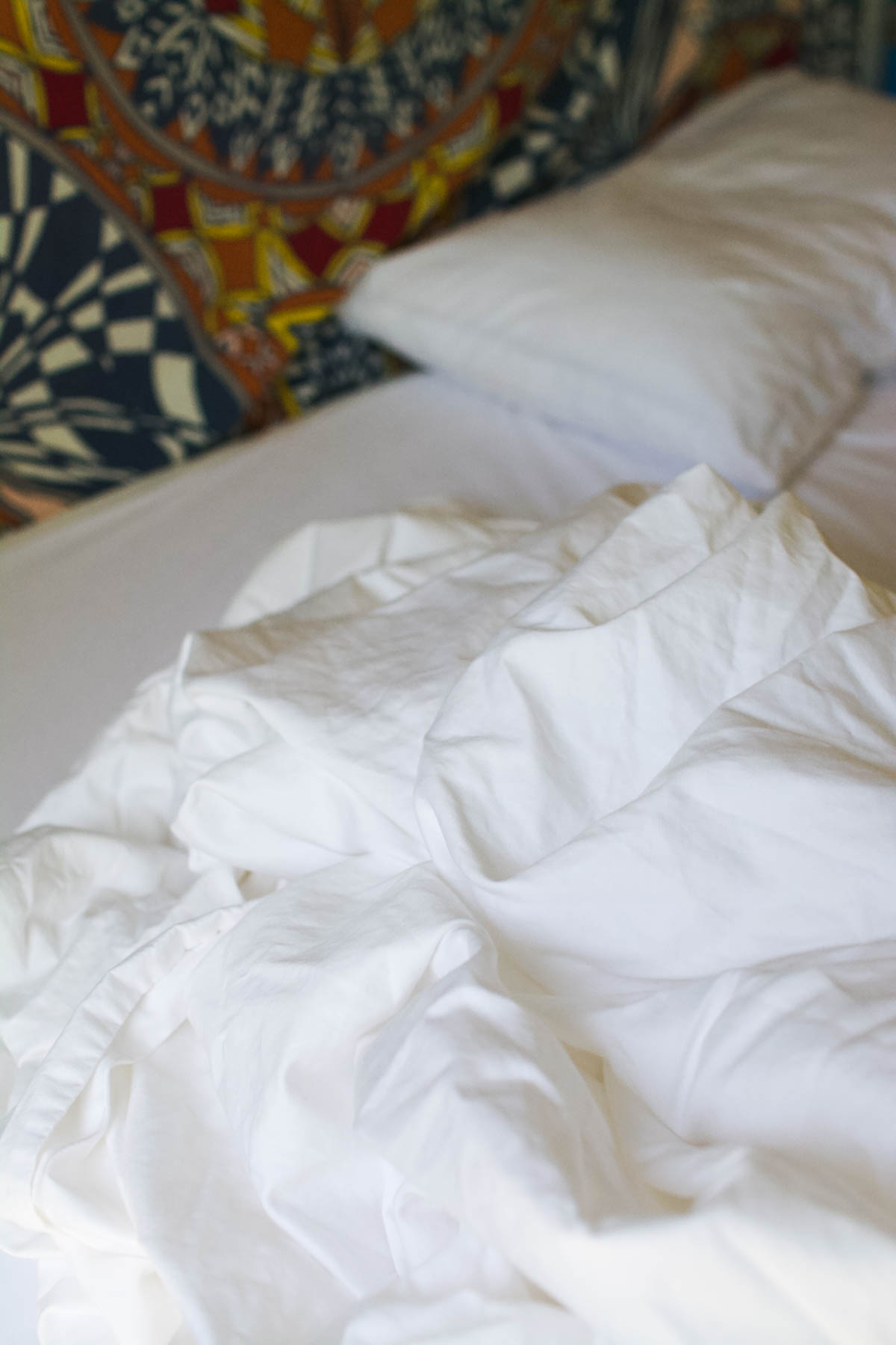 White sheet set piled on top of an unmade bed. 