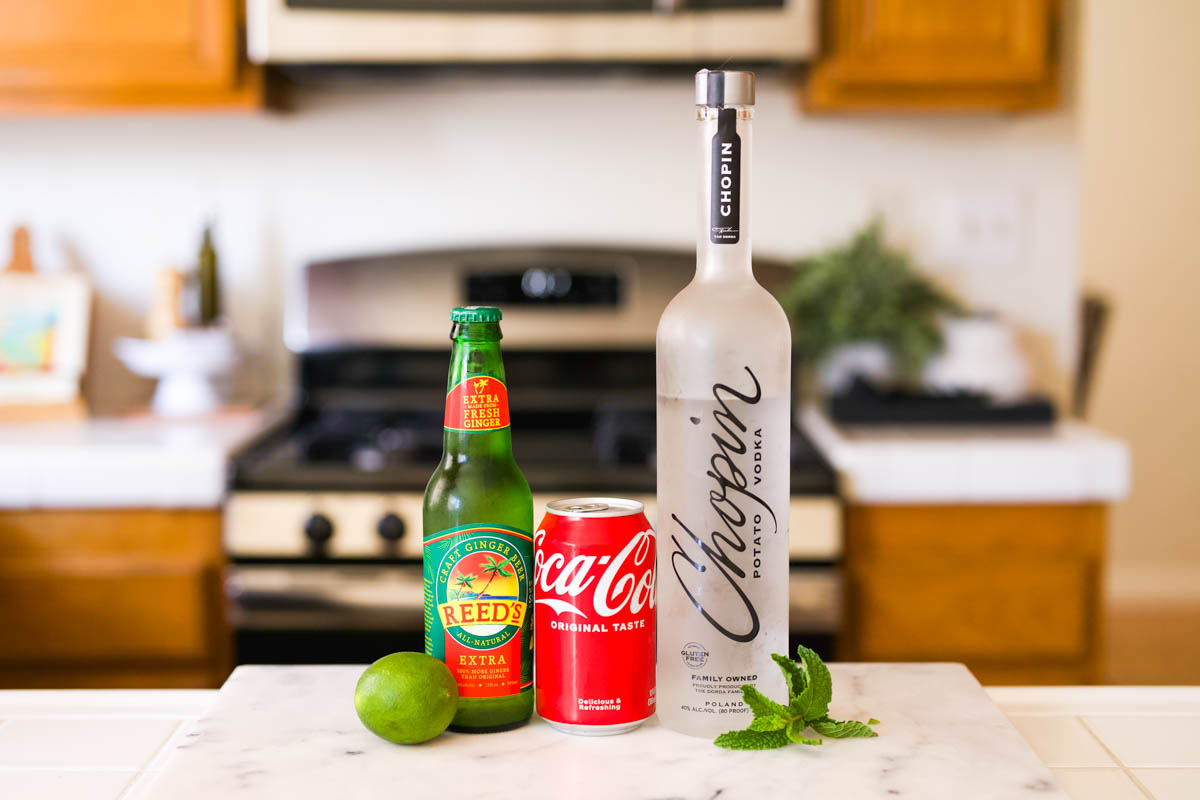 Ingredients to make a Moscow Mule with Coke and vodka on a counter.