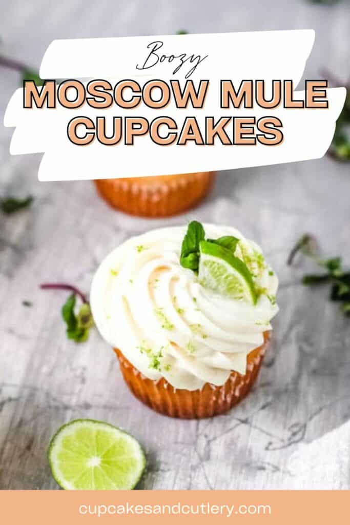Text: Boozy Mocow Mule Cupcakes with a frosted cupcake topped with a lime wedge and mint on a table.