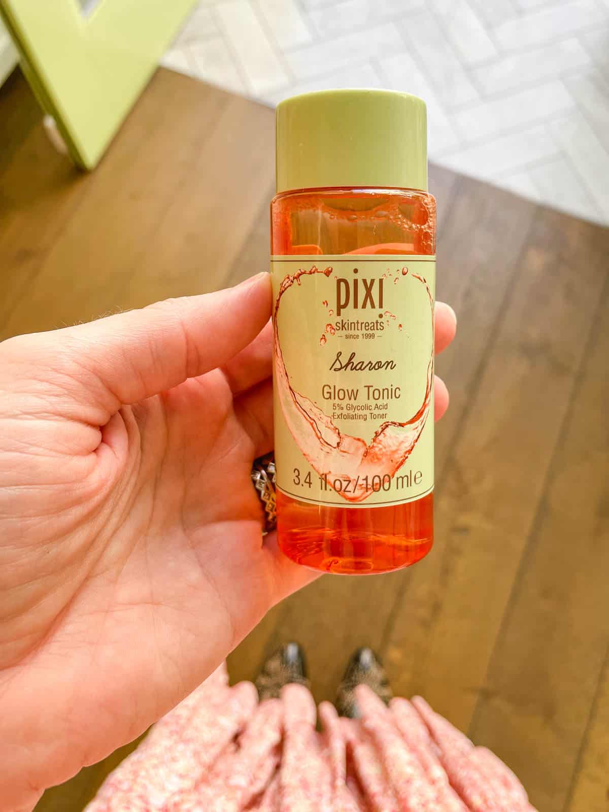 Woman holding a personalized bottle of Pixi cult classic product called Glow Tonic.