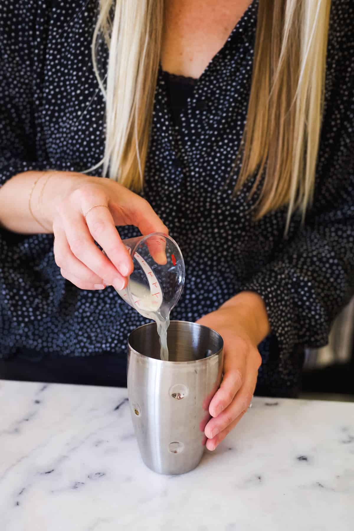 Woman adding fresh lime to a cocktail shaker.