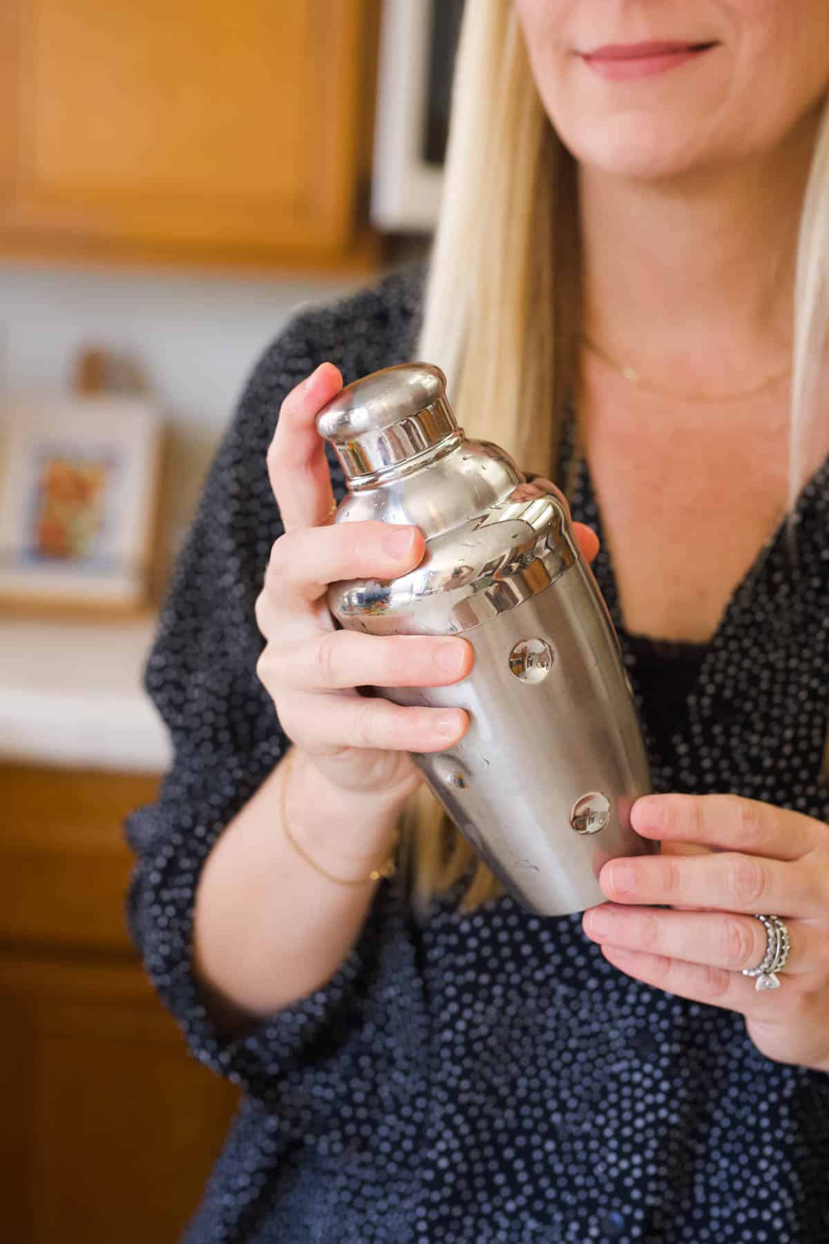 Woman shaking a cocktail in a cocktail shaker.
