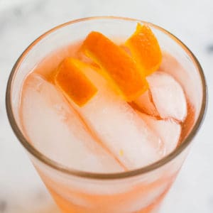 Close up of the top of a cocktail with a citrus twist made from an orange peel.
