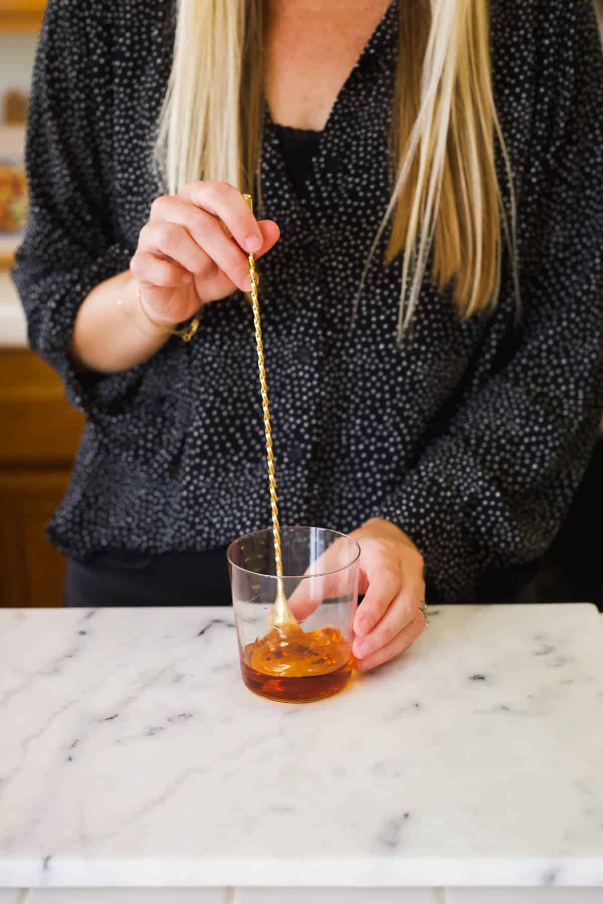 Woman stirring a cocktail made with bourbon and Fireball whiskey.