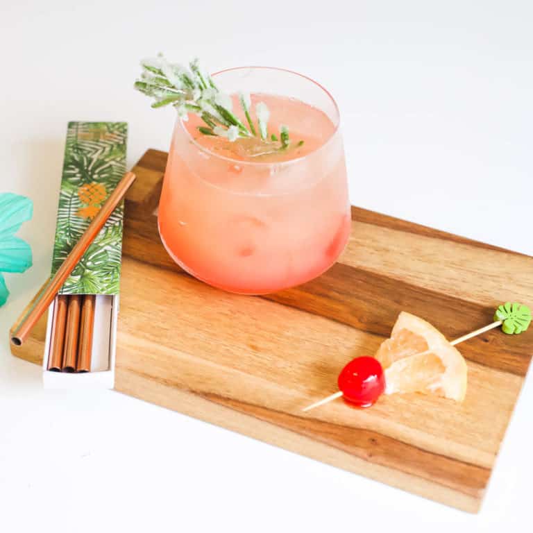 Close up of a cocktail with an herb garnish and other garnish ideas around it on a tray.