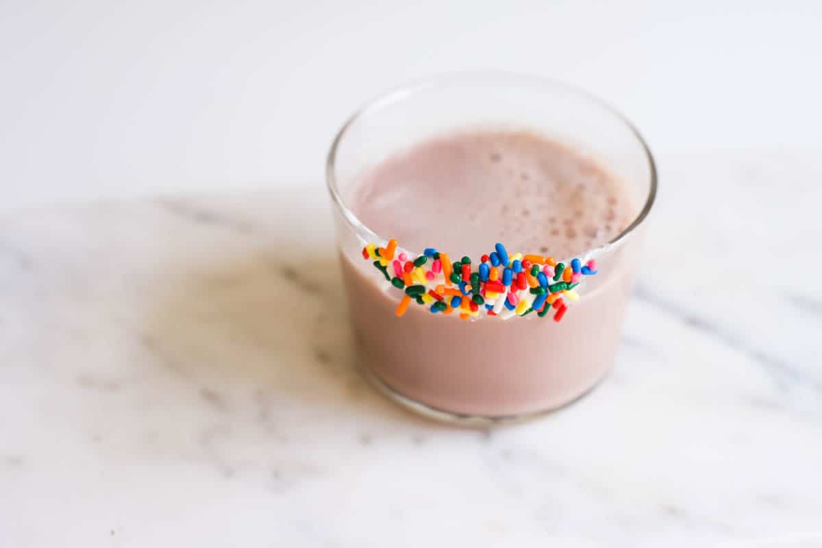 A drink with a glass rim of frosting and sprinkles.