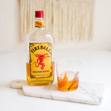 A cocktail glass on a table with Fireball Old Fashioned.