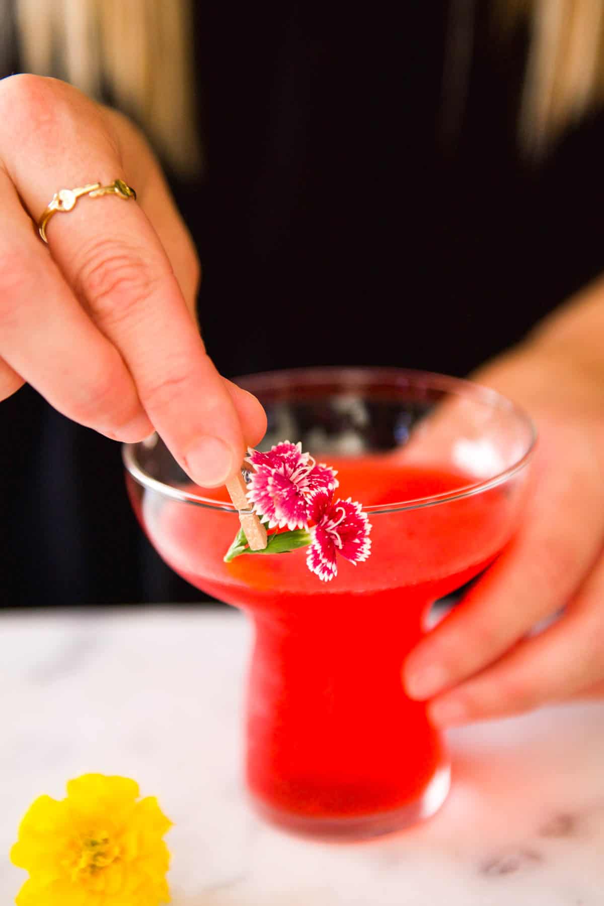 Using a mini clothespin to clip flowers to a cocktail glass.