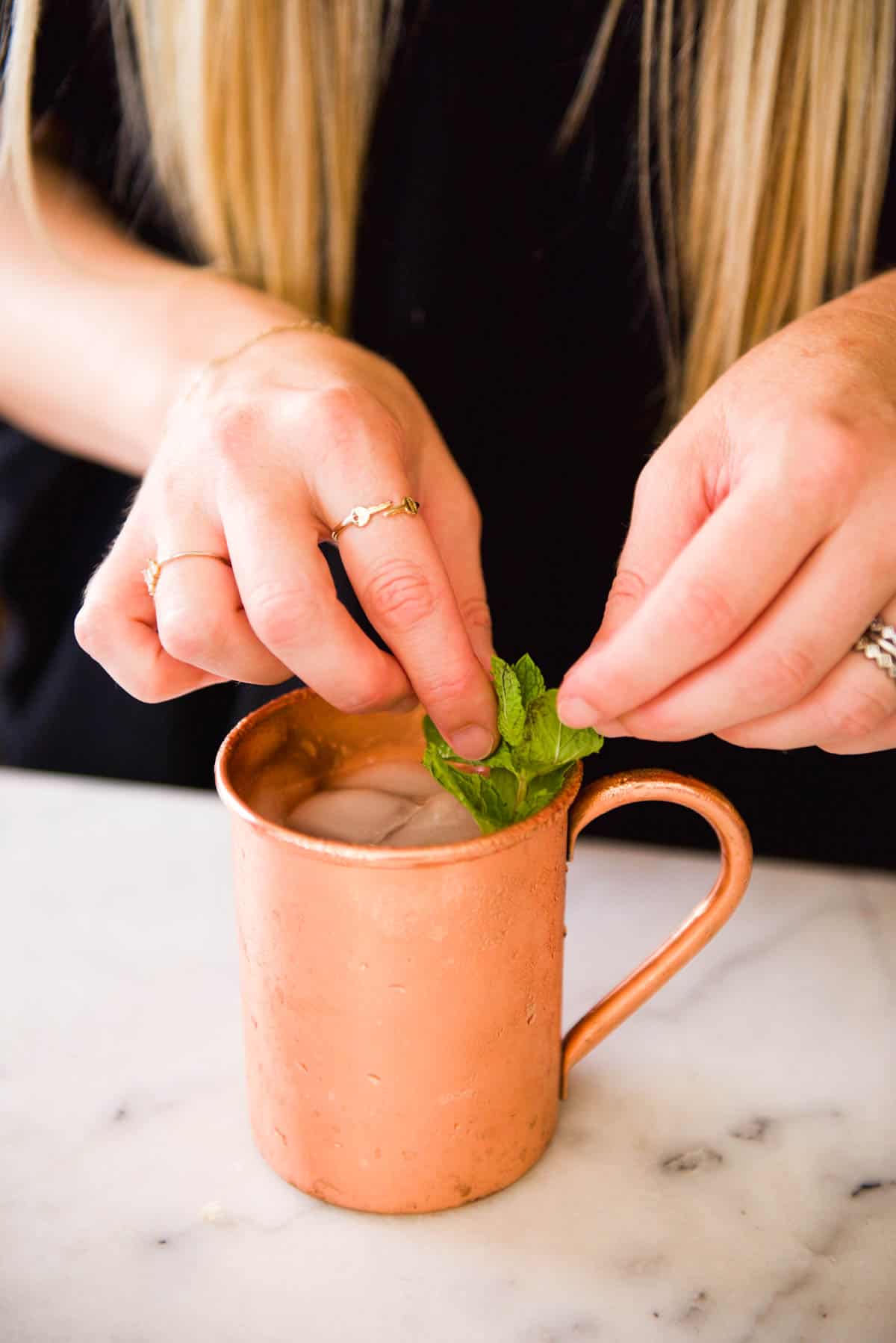 Adding fresh mint to a cocktail as a garnish.