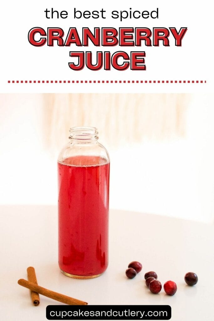 Text: The best spiced cranberry juice with a bottle holding spice infused cranberry juice with spices on the table around it.