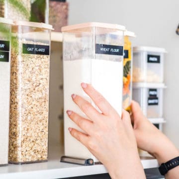 Close up of woman's hands on a food container on a shelf.