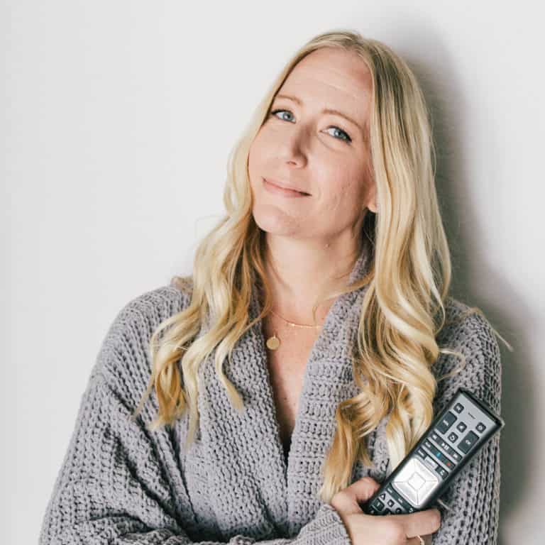 Mom holding a remote control in a cozy sweater.