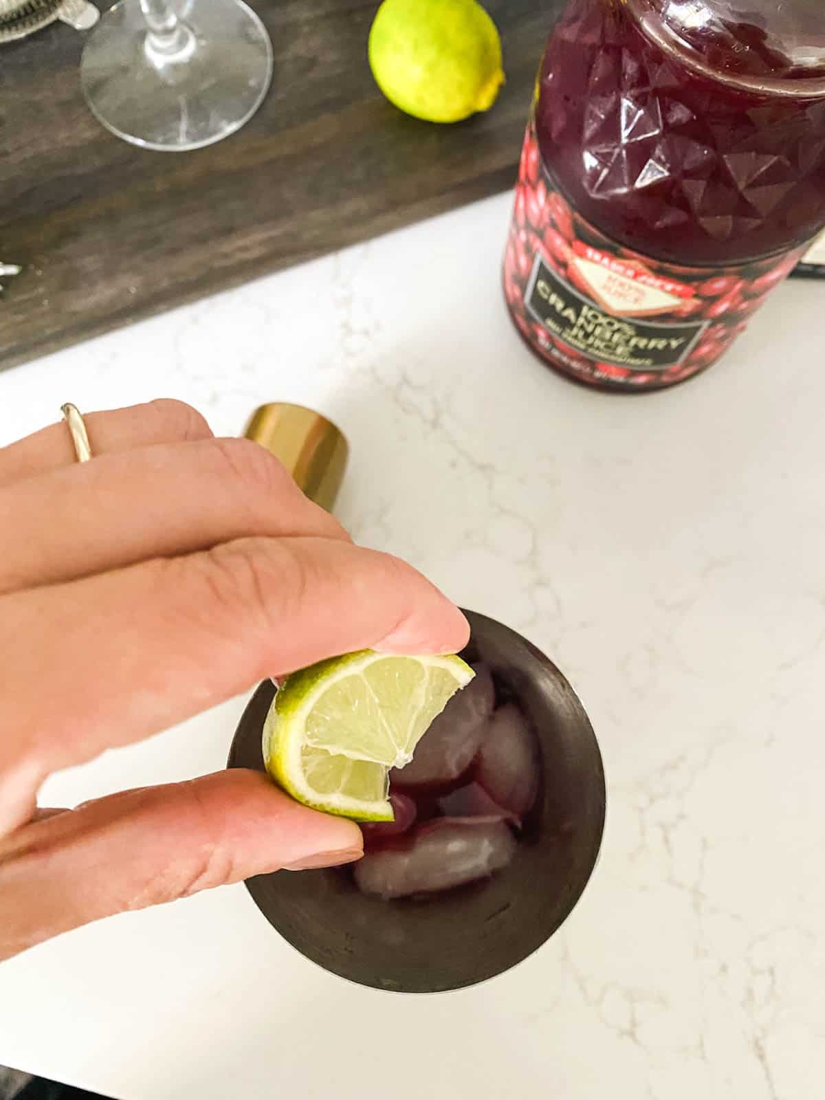 A woman squeezing fresh lime into a cocktail shaker.