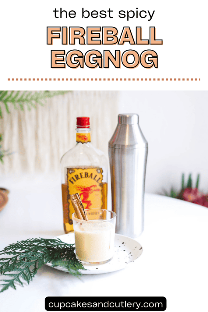 Text: The Best Spicy Fireball Eggnog with a glass holding eggnog on the table with a cocktail shaker and bottle of Fireball.