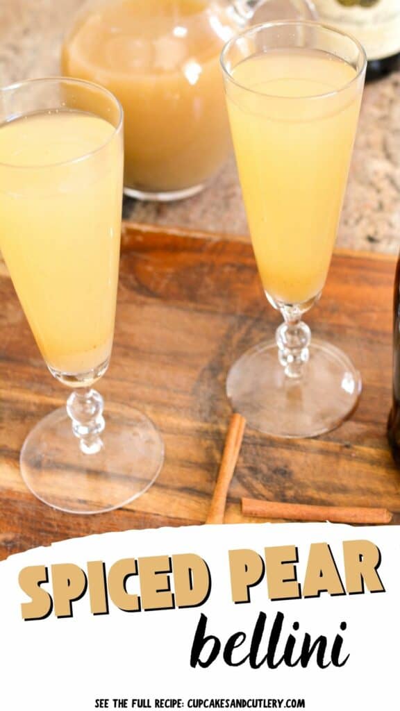 Text: Spiced Pear Bellini with 2 champagne flutes on a cutting board next to spiced pear nectar and cinnamon sticks.