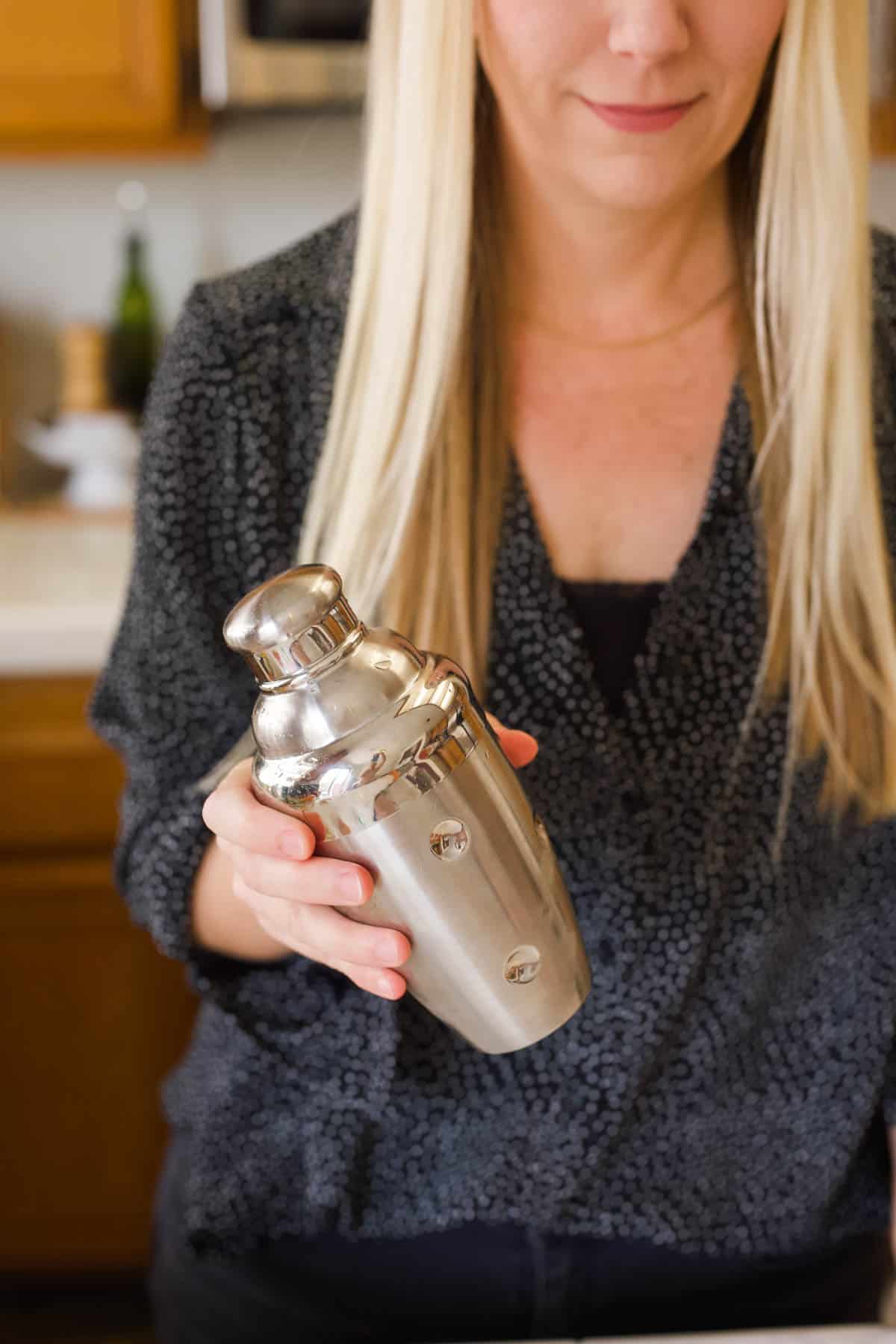 Woman shaking a cocktail shaker.