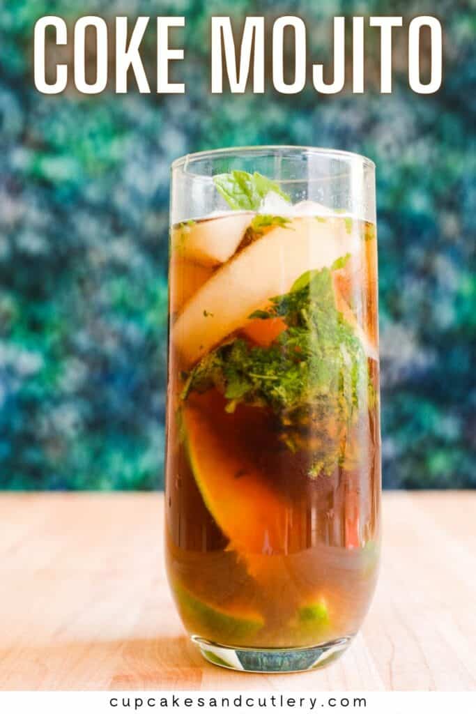 Text: Coke Mojito with a tall glass holding a glass of Coke with ice and fresh mint leaves and limes on a table.