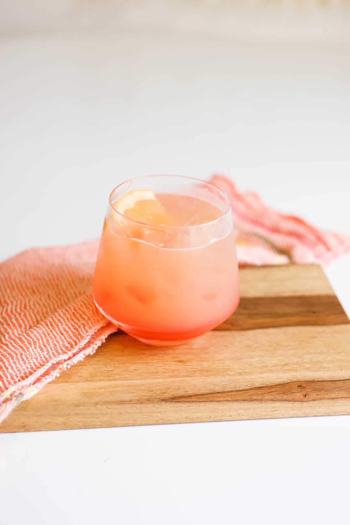 Pretty sunrise cocktail in a short cocktail glass on a wooden board on a table.