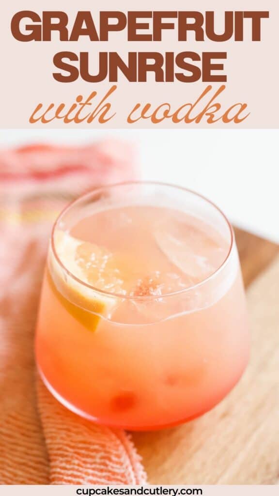 Text: Grapefruit Sunrise with Vodka with a pretty orange and pink cocktail on a table with a piece of grapefruit for a garnish.