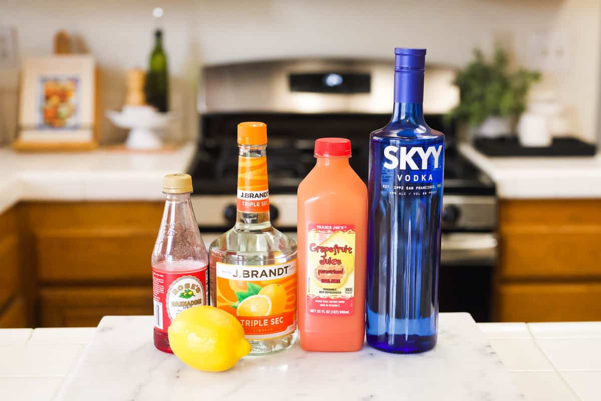 Ingredients needed to make a Grapefruit Sunrise cocktail with vodka on a counter.
