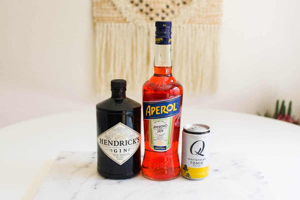 Ingredients on a table to make a cocktail with Aperol, Gin and Tonic.