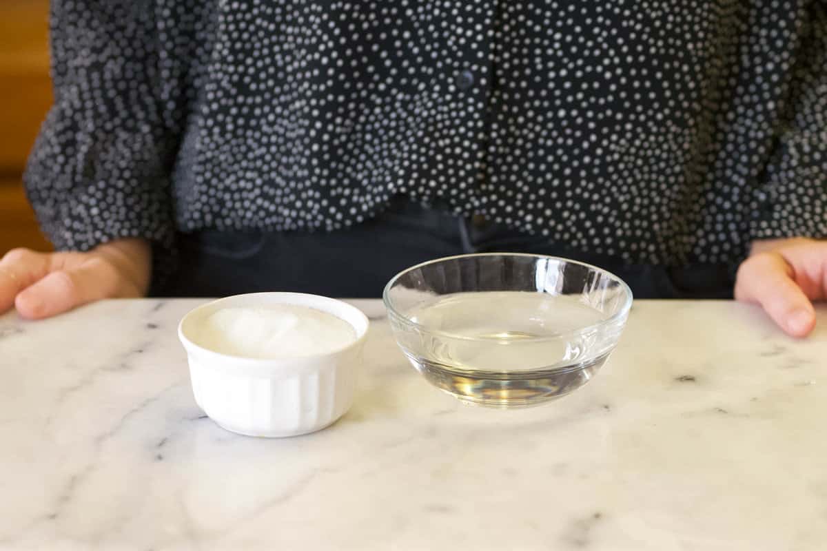 A bowl of sugar next to a bowl of water on the counter.