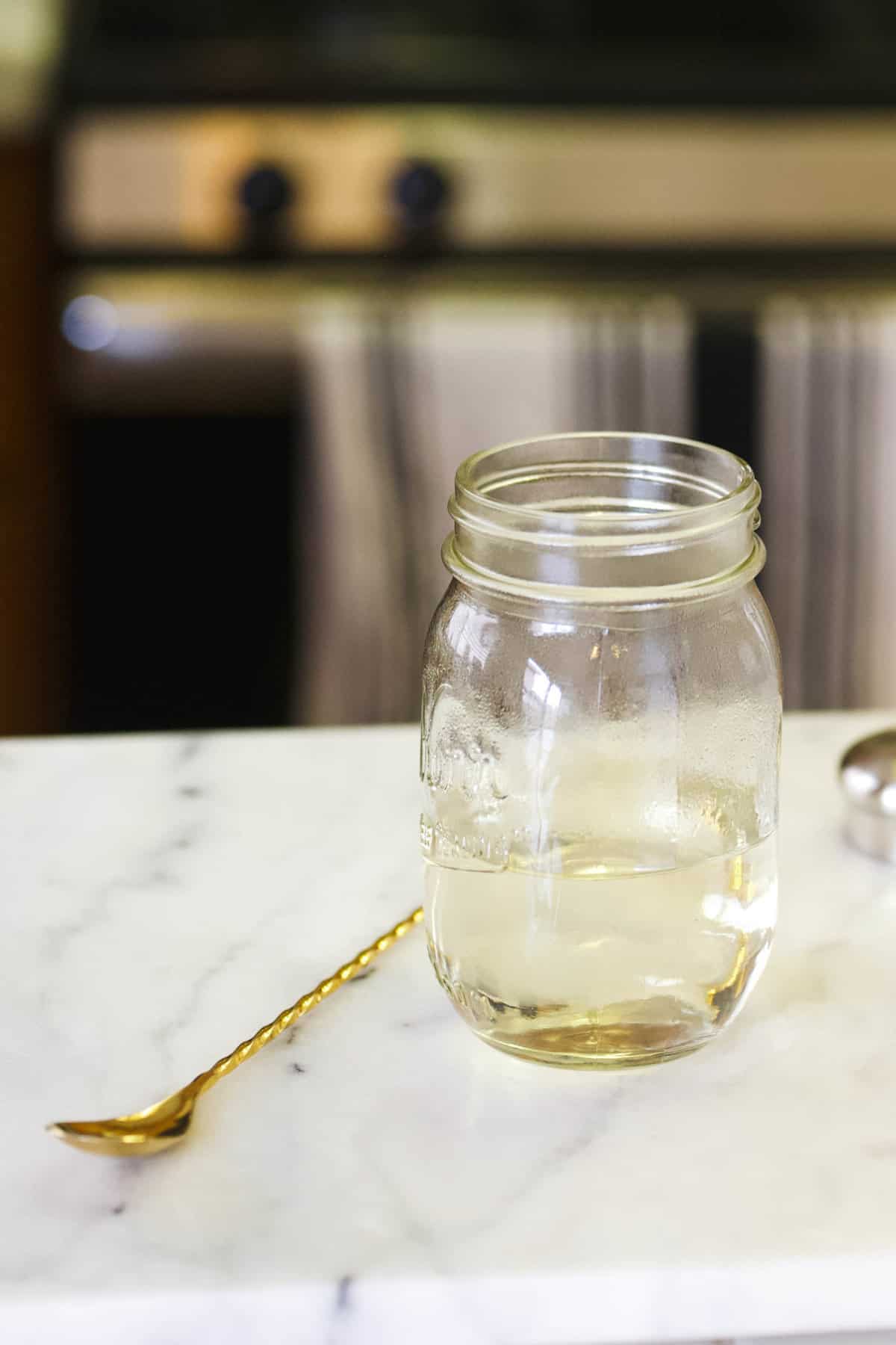 Microwave Simple Syrup in a mason jar on a counter next to a bar spoon.