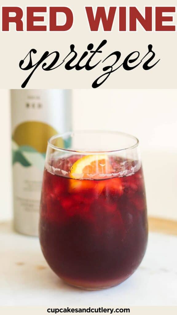 Text: Red Wine Spritzer with a stemless wine glass holding a red wine with an orange garnish on a table with an aluminum wine bottle behind it.