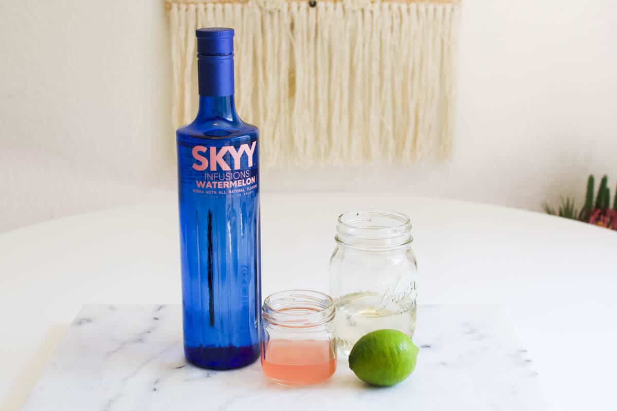 Ingredients to make a watermelon vodka gimlet on a counter.