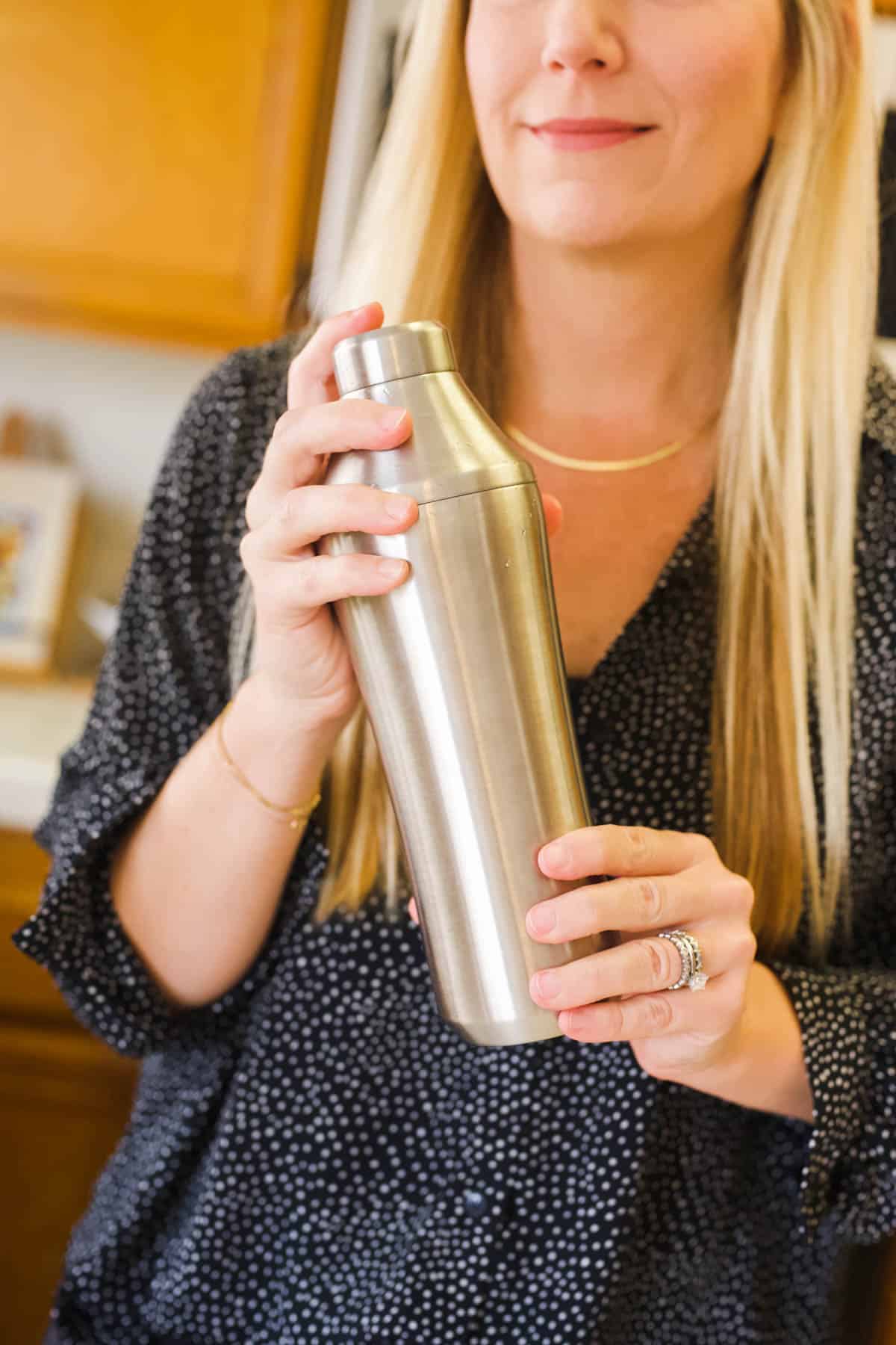 A woman shaking a cocktail in a cocktail shaker.