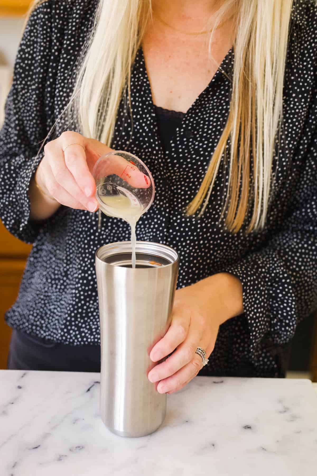 A woman adding fresh lime juice to a cocktail shaker.