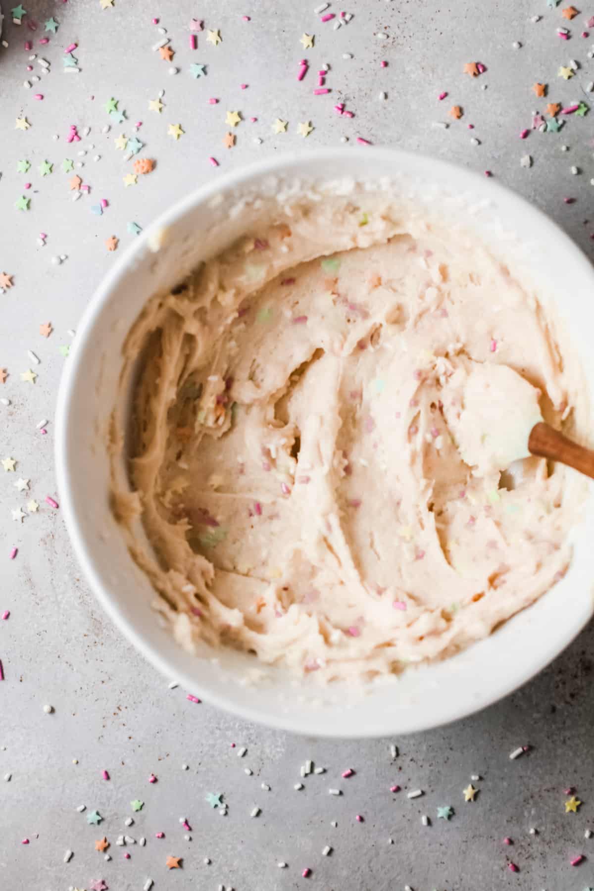 A bowl of cake mix batter and a spatula after sprinkles have been folded in.