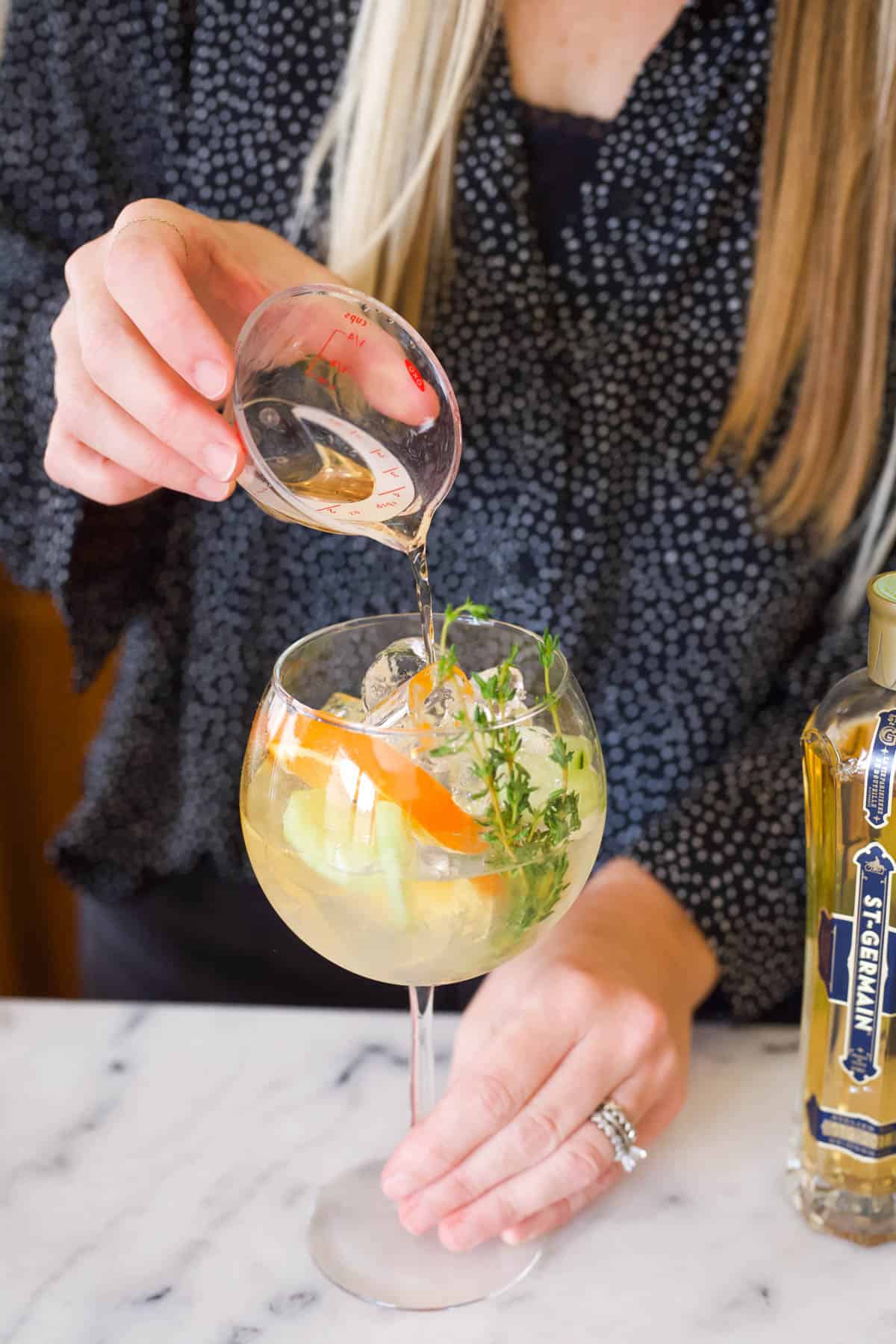 Woman adding St Germain to a Cointreau cocktail.
