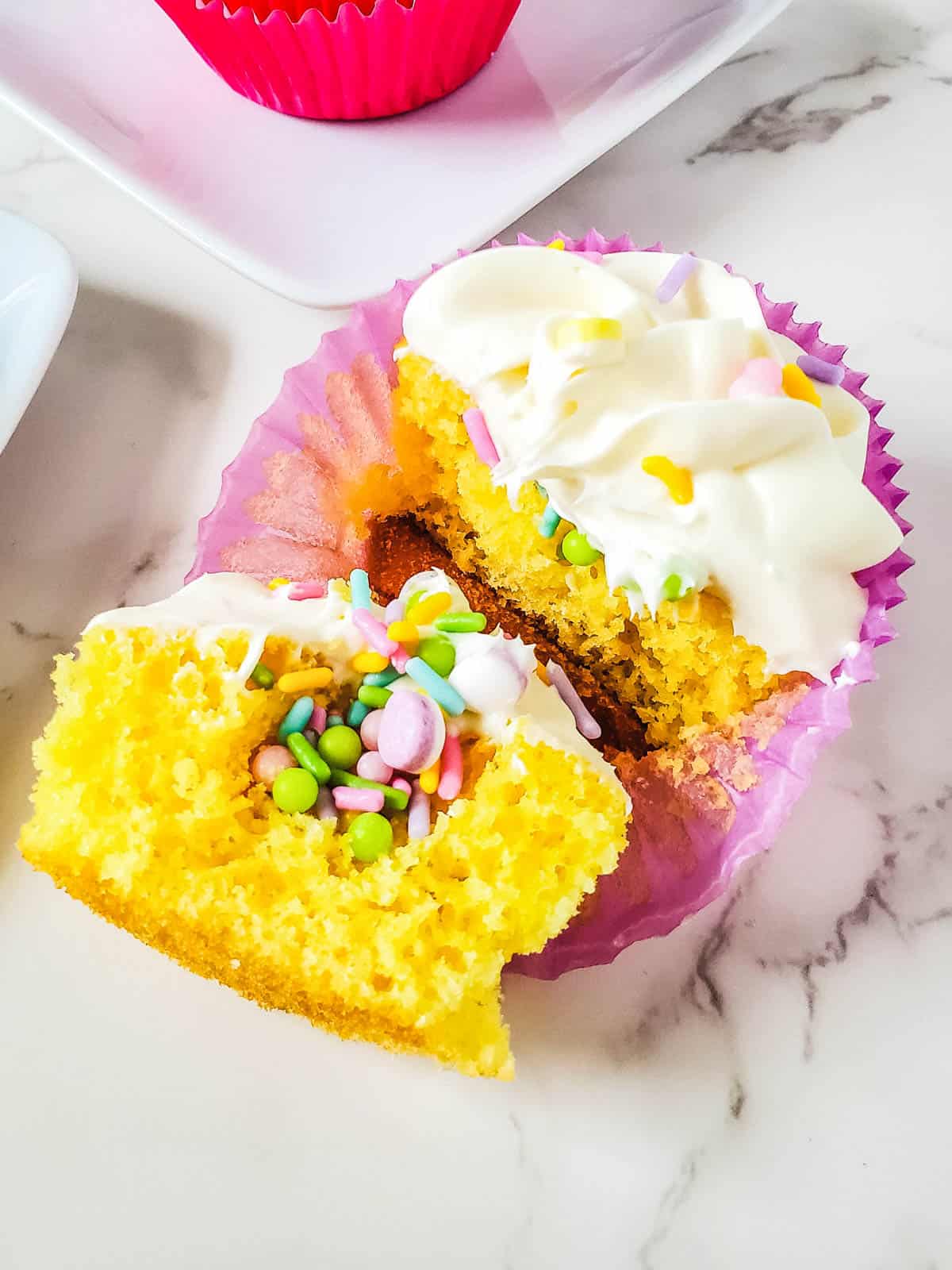 Close up of a Easter cupcake cut open to reveal Easter colored sprinkles hidden inside.