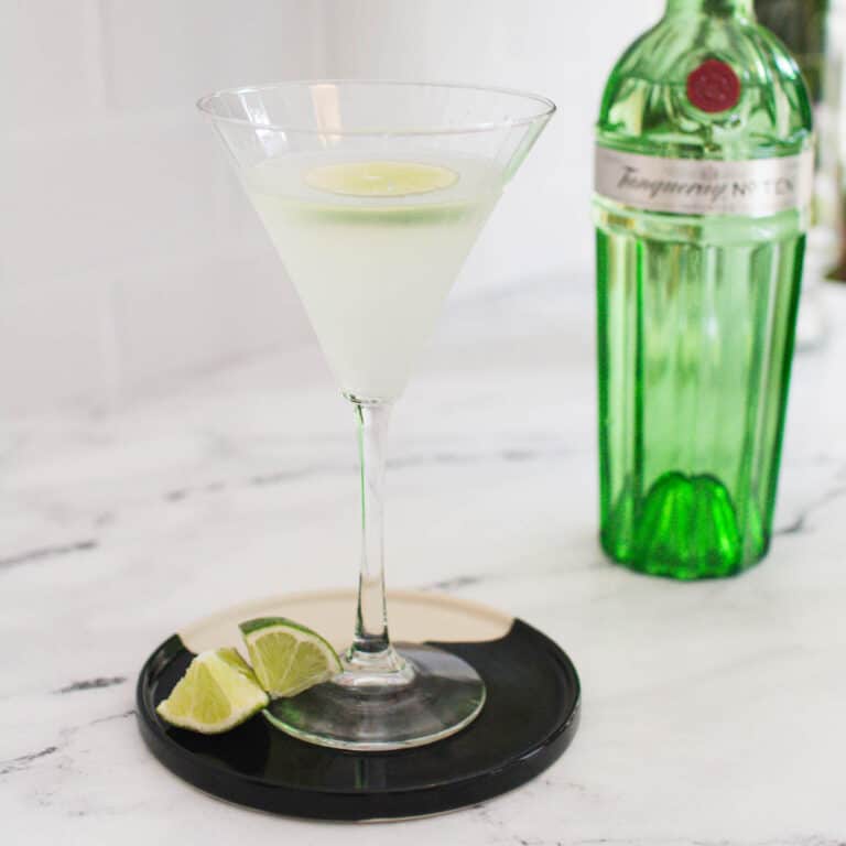 Gin gimlet with a bottle of gin gin the background.