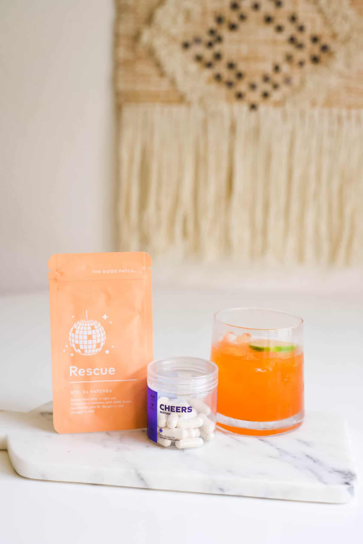 A cocktail on a tray with Cheers hangover pills and supplement patch.