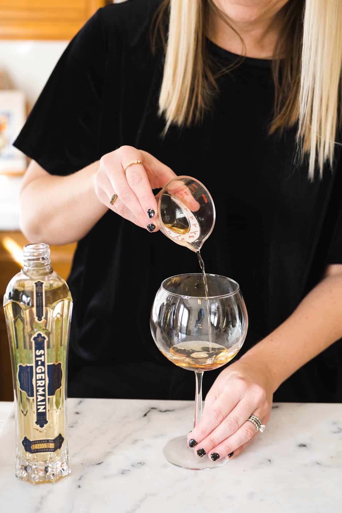 Woman measuring St Germain into a spritz glass.