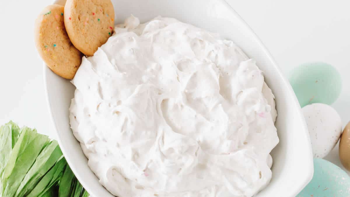 Easter dessert dip in a white bowl with 2 cookies garnishing it.