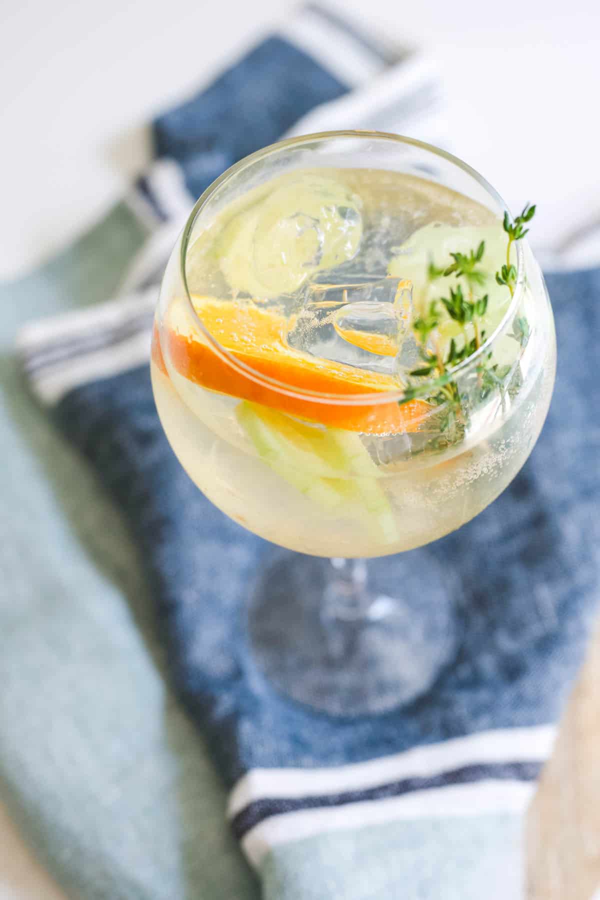 A large wine glass filled with a Cointreau prosecco cocktail on top of a blue striped towel.