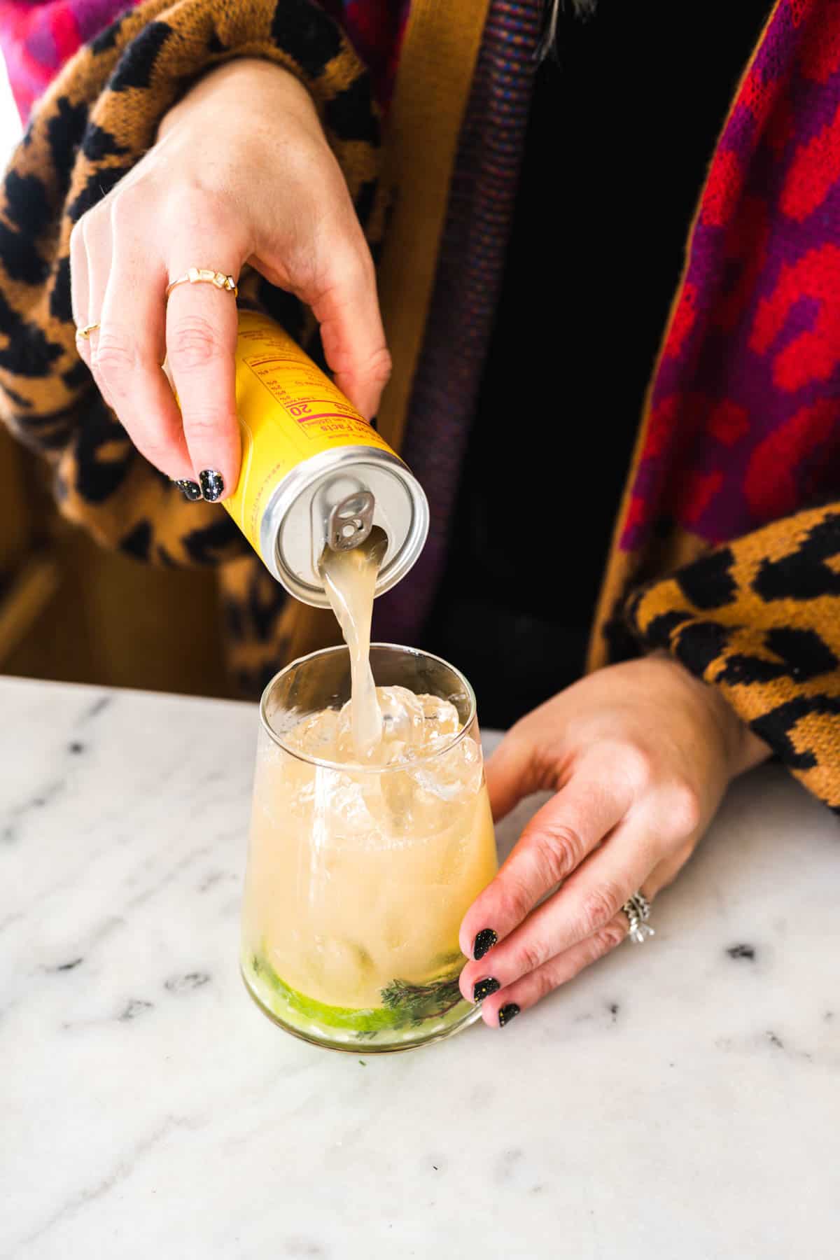 Woman pouring soda into a cocktail glass.
