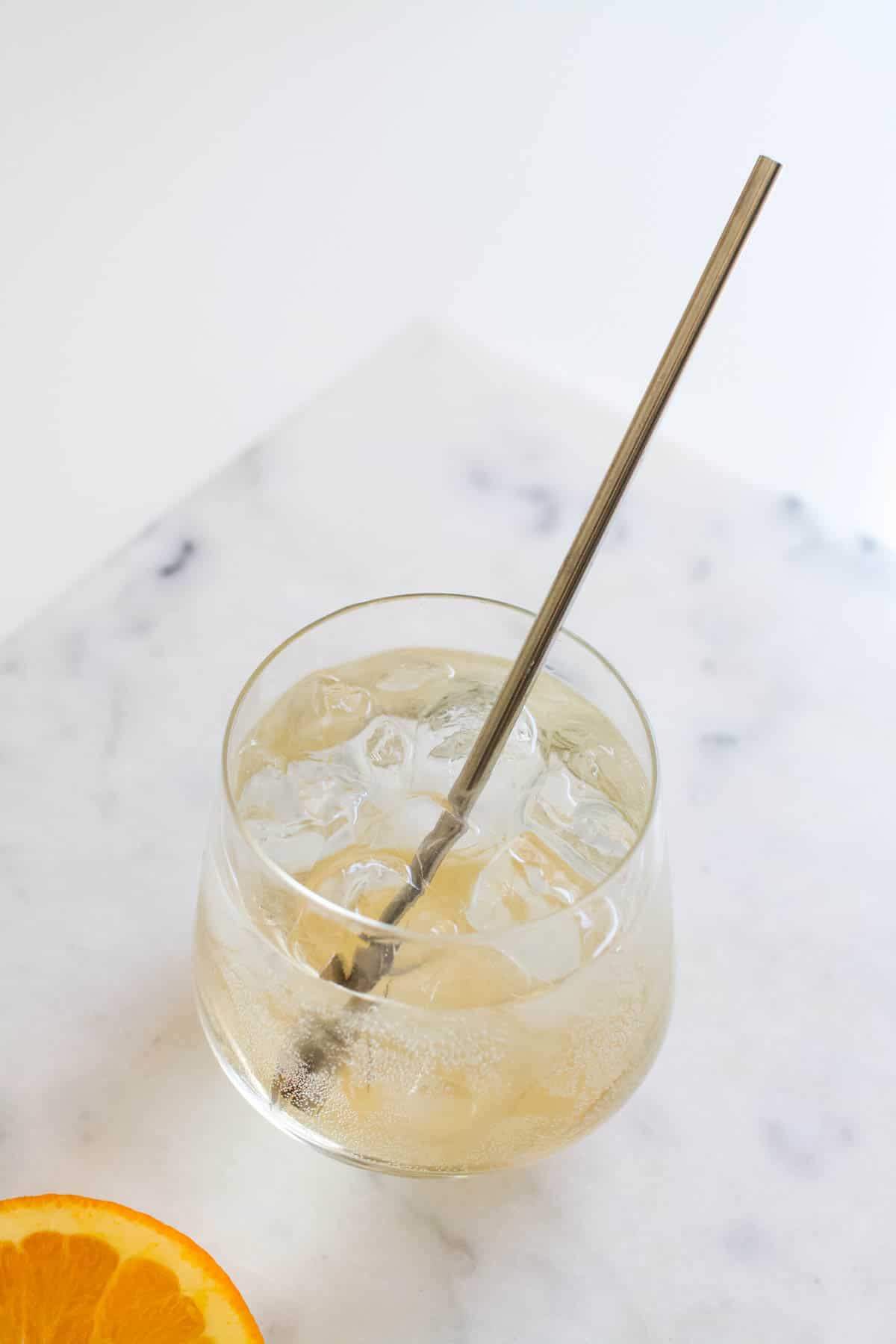Glass of St Germain and Club Soda being stirred with a metal straw.