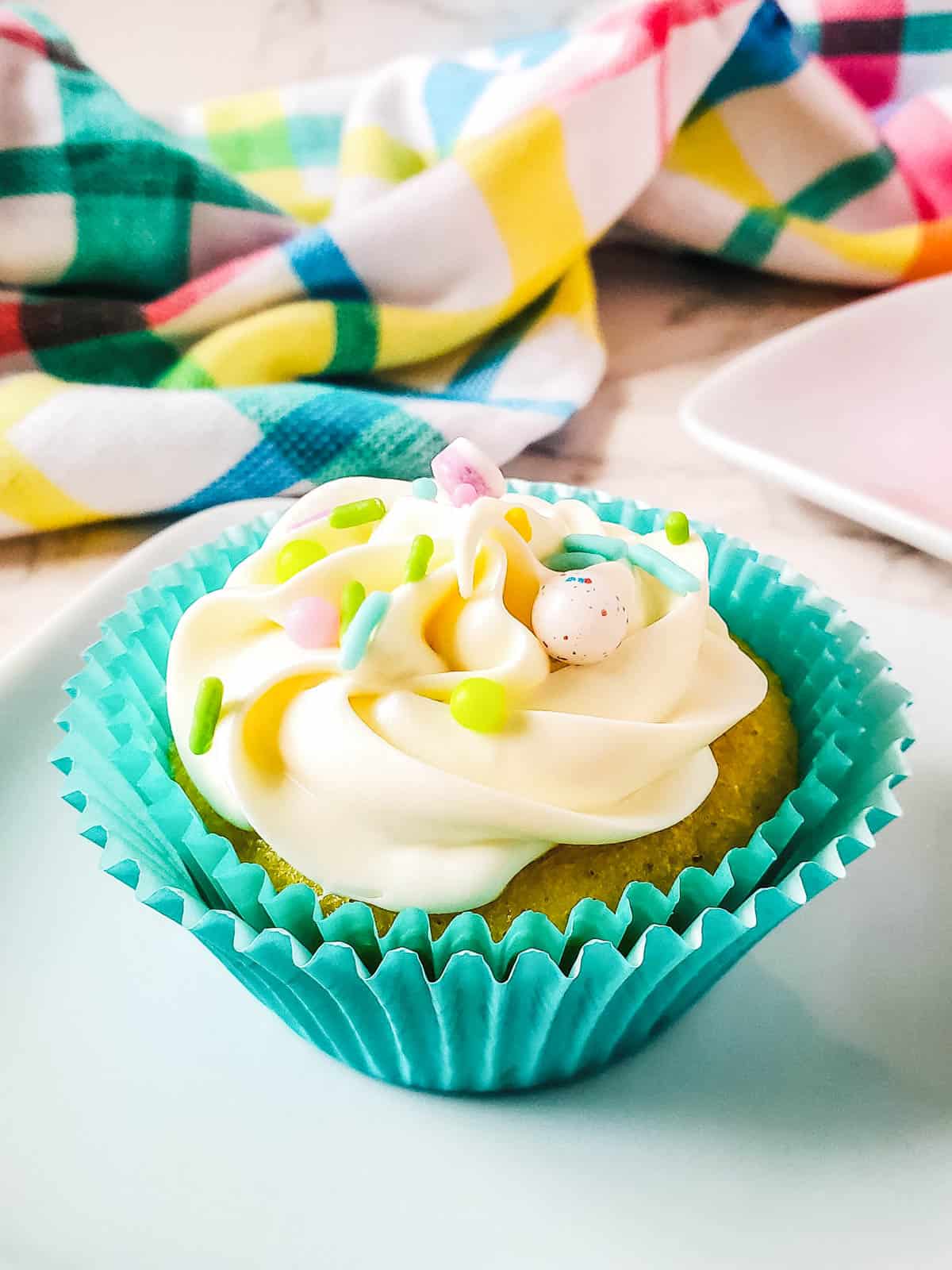 A frosted cupcake topped with sprinkles and Jelly Beans for Easter.