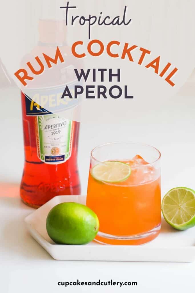 Text: Tropical rum cocktail with Aperol - an Aperol cocktail on a white plate surrounded by fresh limes in front of a bottle of Aperol liqueur.