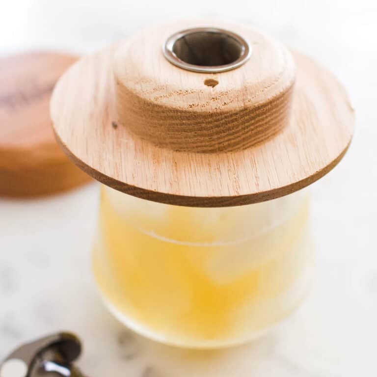 Square image of a high ball glass topped with the aged and charred cocktail smoker.