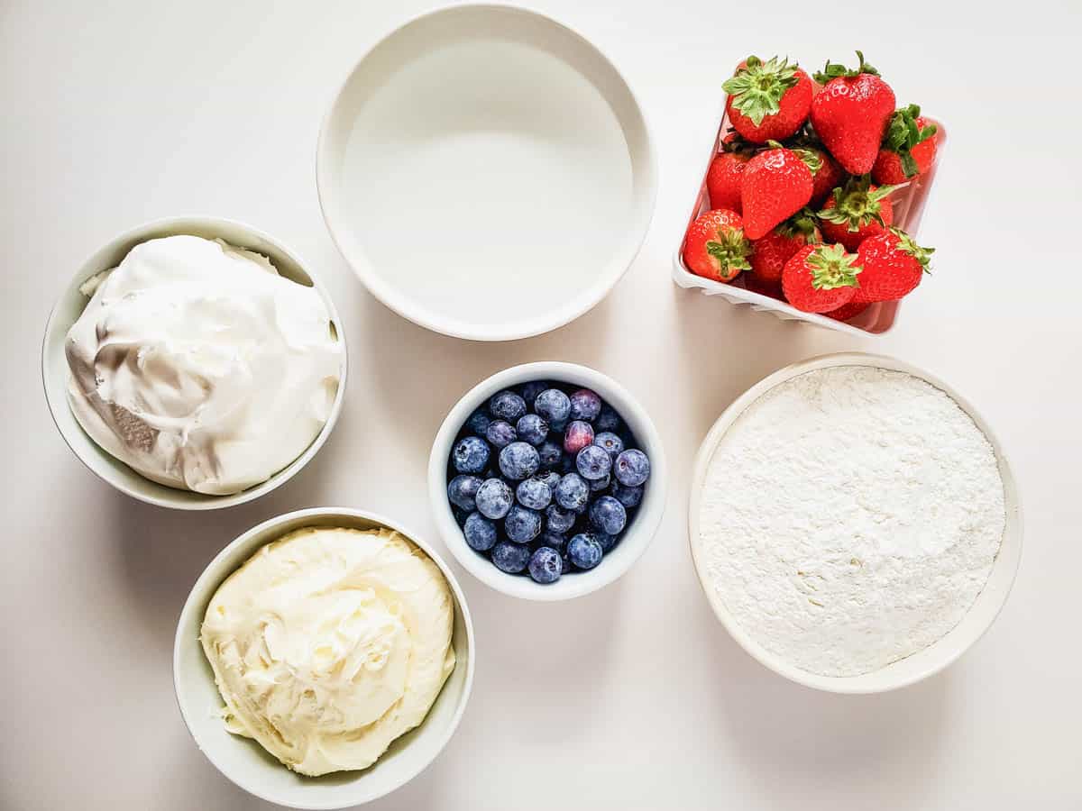 Ingredients to make angel food cake cupcakes that are topped with berries.