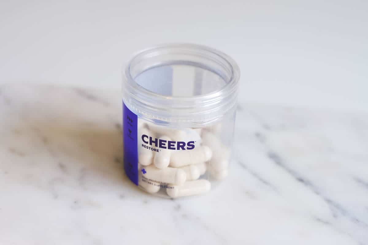 A small clear jar of Cheers Restore on a marble surface.